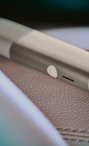 جهاز IQOS ILUMA ONE على سطح جلدي.